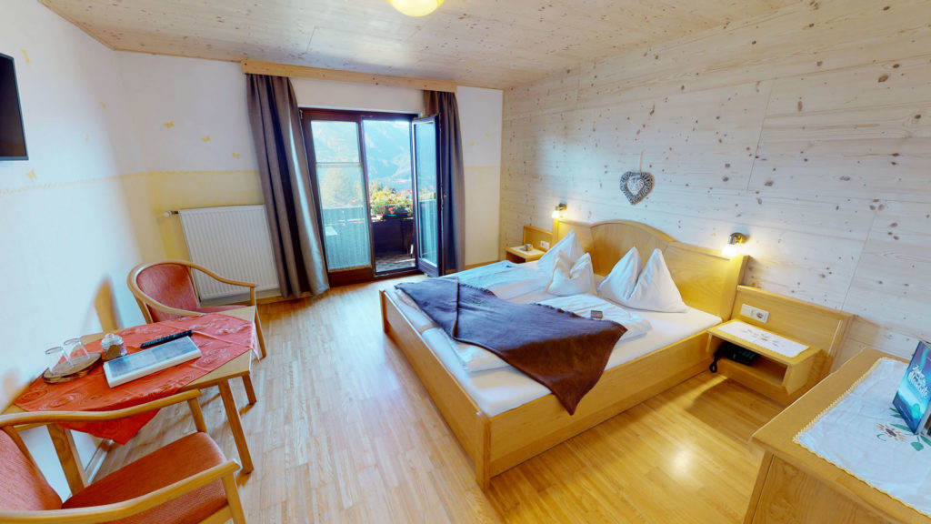 Doppelzimmer mit Holzmöbeln und Zugang zum Balkon
