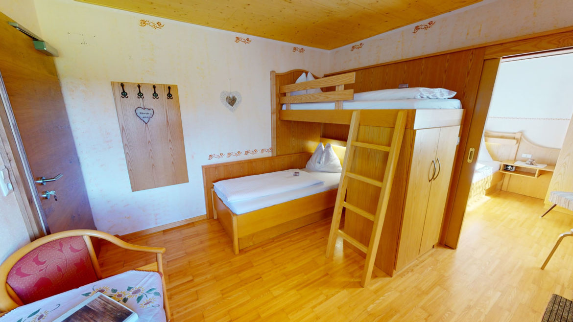 Familienzimmer im Berghotel Presslauer mit Stockbett im Kinderschlafzimmer und Blick ins Elternzimmer