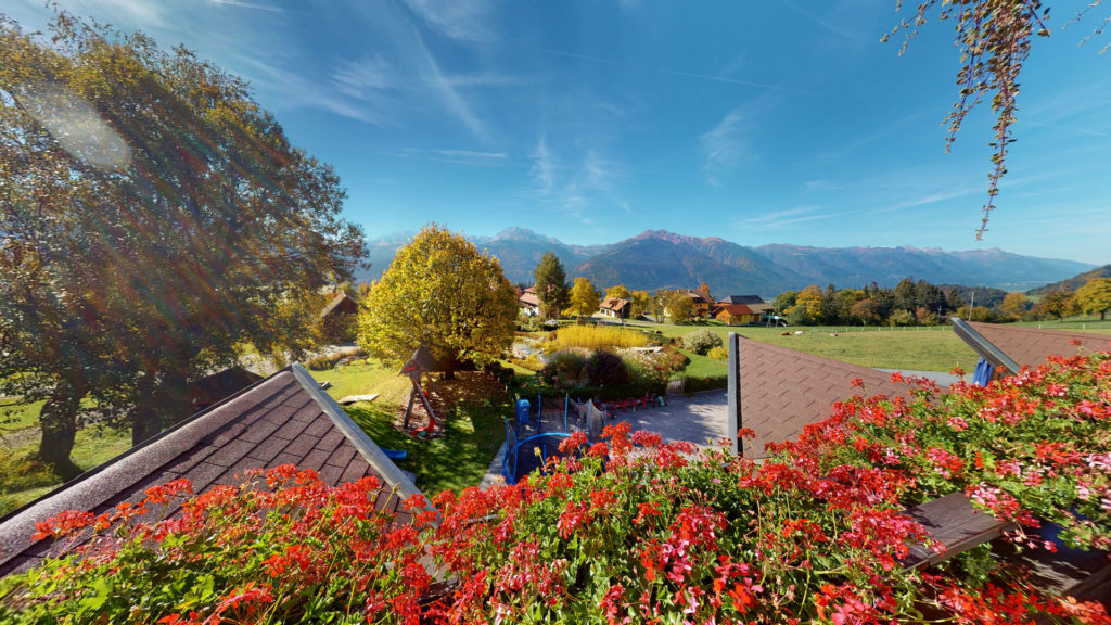 Blick vom Balkon eines Familienzimmers über Blumenkästen ins Tal und auf die Berge