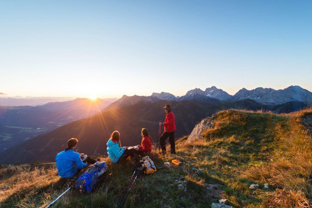 Escursionisti in sosta su un alpeggio della Lesachtal alla luce del tramonto