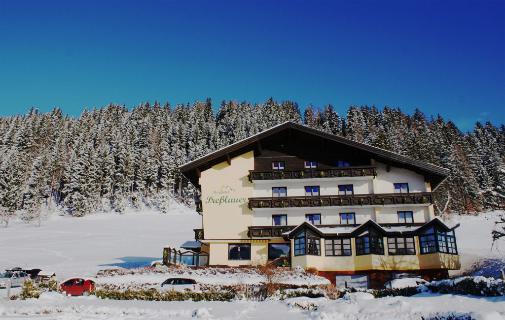 Das Berghotel Presslauer im Winter vor verschneitem Wald