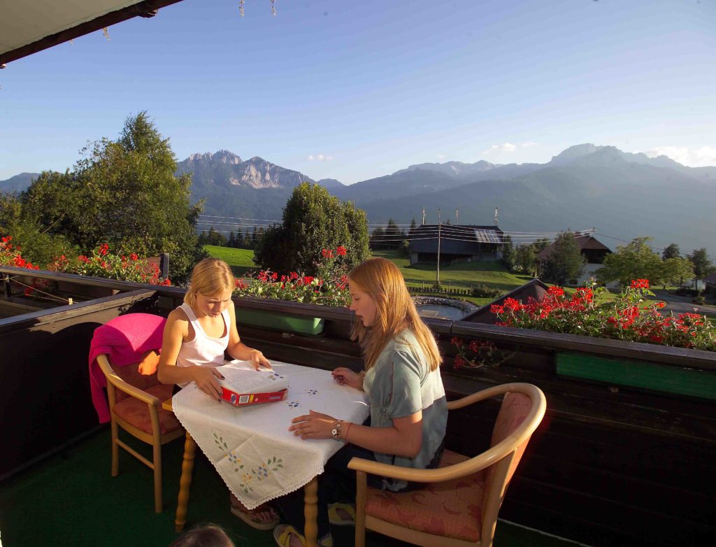 Zwei Gäste am gedeckten Tisch auf dem Balkon mit Blick auf die Berge