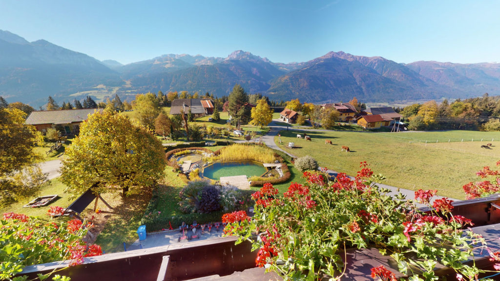 Vista dal balcone sul giardino con il laghetto balneabile e sulle montagne