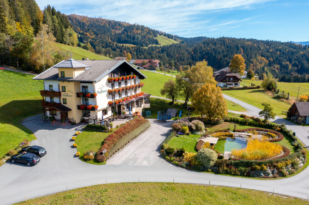 Luftaufnahme des Berghotels Presslauer mit Naturschwimmteich, Garten und Wiesen im Herbst