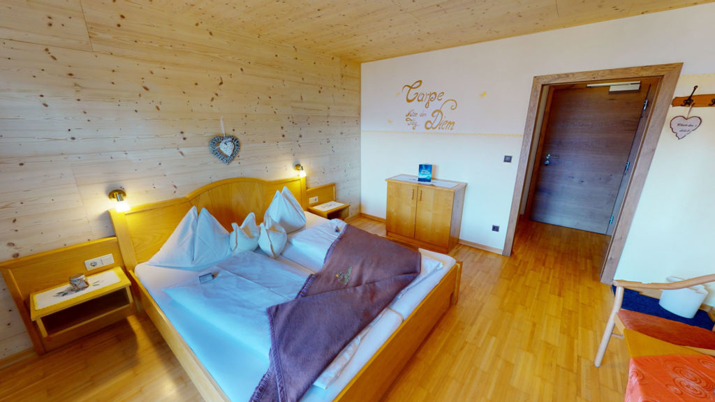 Doppelzimmer mit Holzbett und Tür zum Flur im Berghotel Presslauer