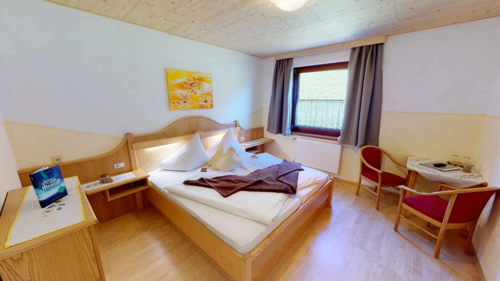 Camera doppia senza balcone con letto in legno e parquet al Berghotel Presslauer