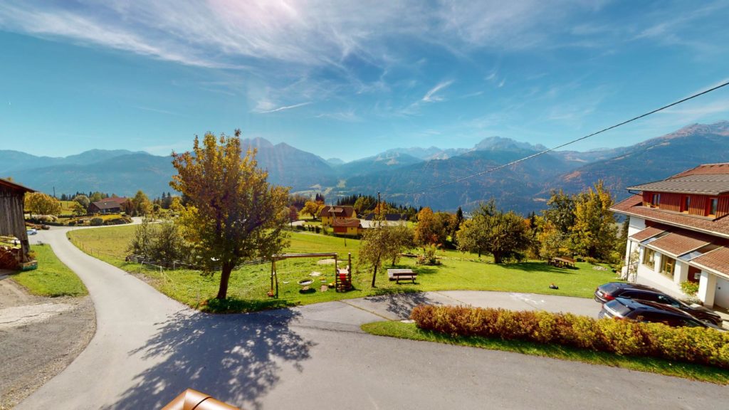 Vista da un appartamento sul giardino e sui prati verso la valle e le montagne