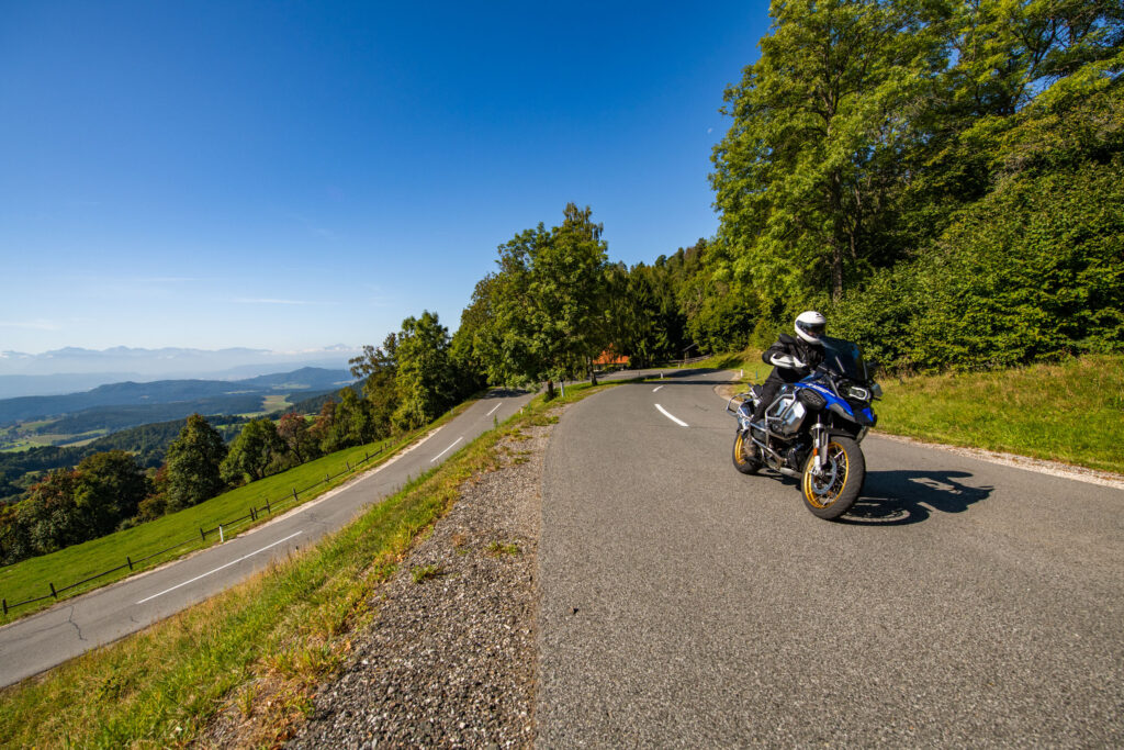 Motorcyclist on a mountain road at the edge of a forest with a view into the valley