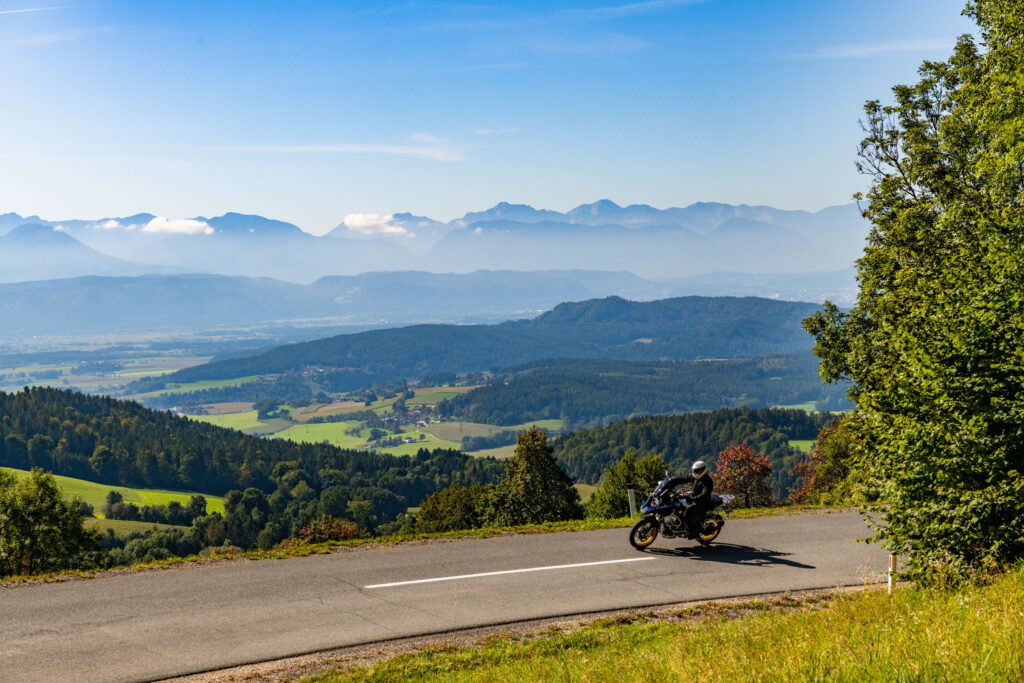 Motorcyclist on a mountain road with a wide view over valleys and mountain ranges