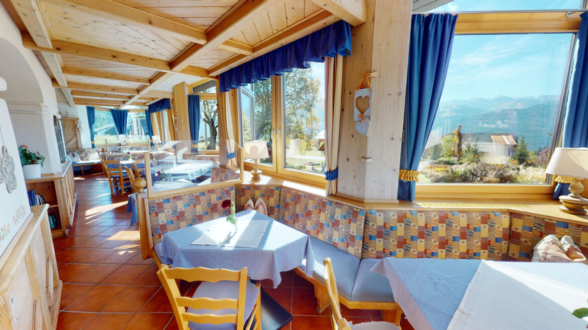 Ristorante del Berghotel Presslauer con tavoli apparecchiati e grandi finestre con vista sui monti