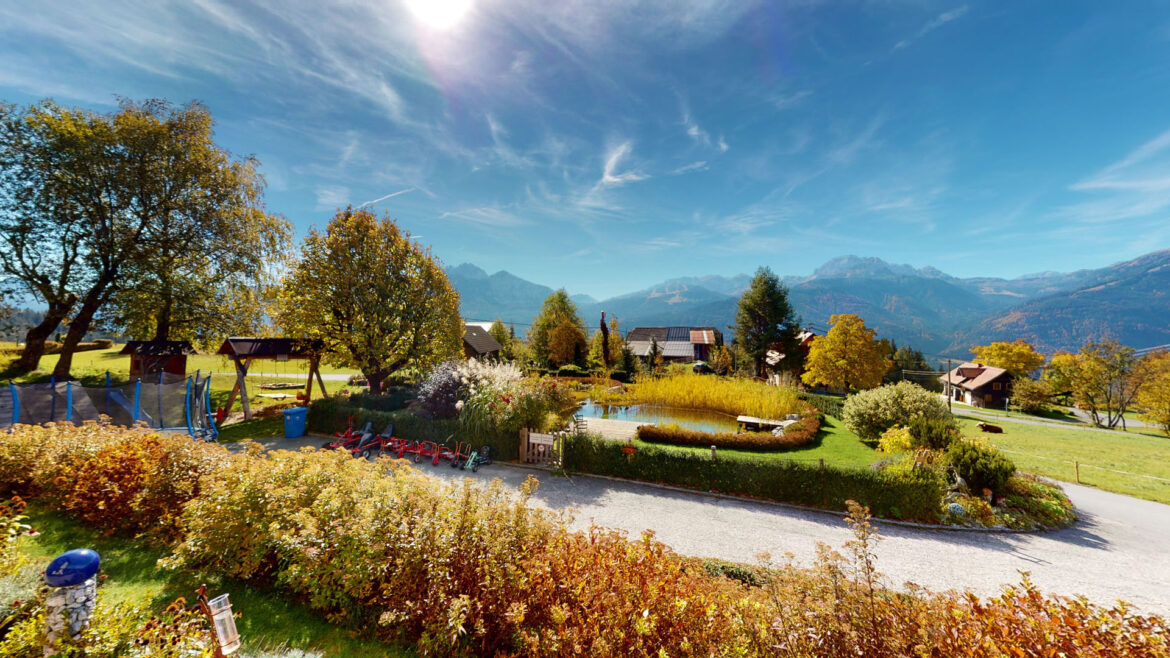 Garten mit Naturschwimmteich und Spielplatz vor dem Berghotel Presslauer, im Hintergrund die Berge