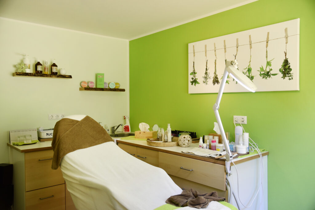 Treatment room in the Kräuter SPA with a massage table and herb pictures on the wall