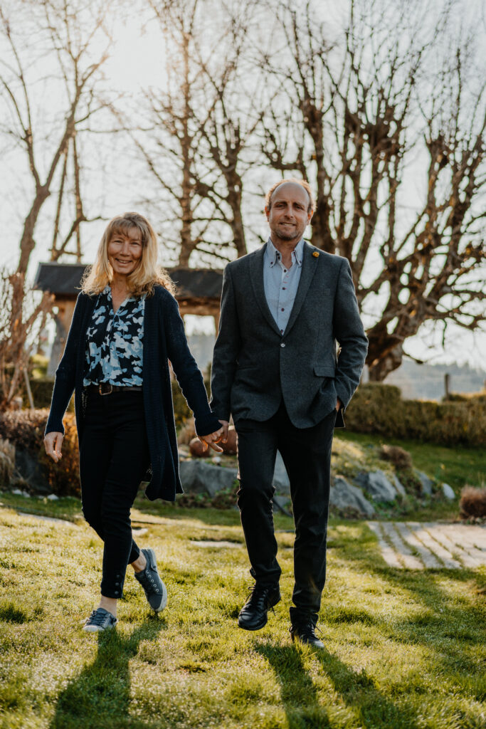Gastgeberpaar der Familie Presslauer Hand in Hand auf der Wiese beim Hotel